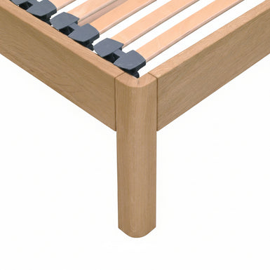 Close-up of a solid oak wooden bed frame with  slatted bed base with dark Gray slat caps.